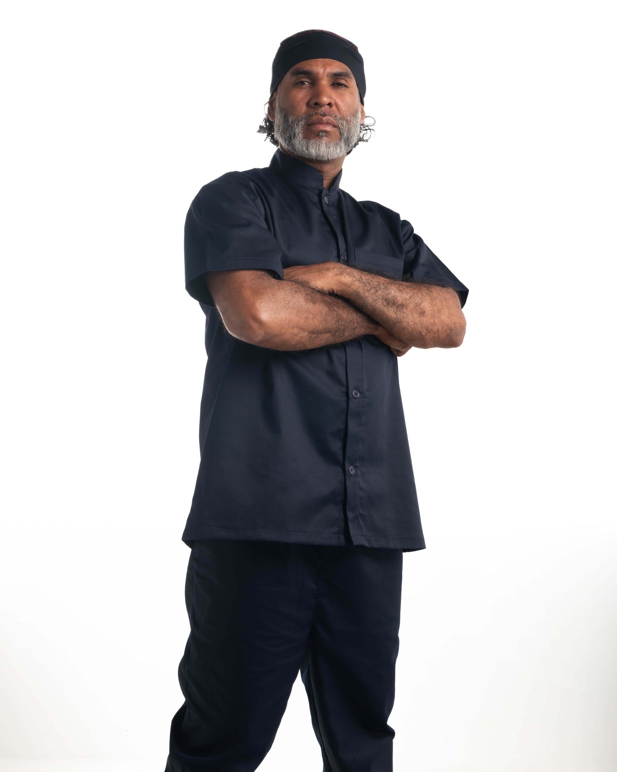 Chef con brazos cruzados luciendo filipina azul marino de manga corta y cuello mao.