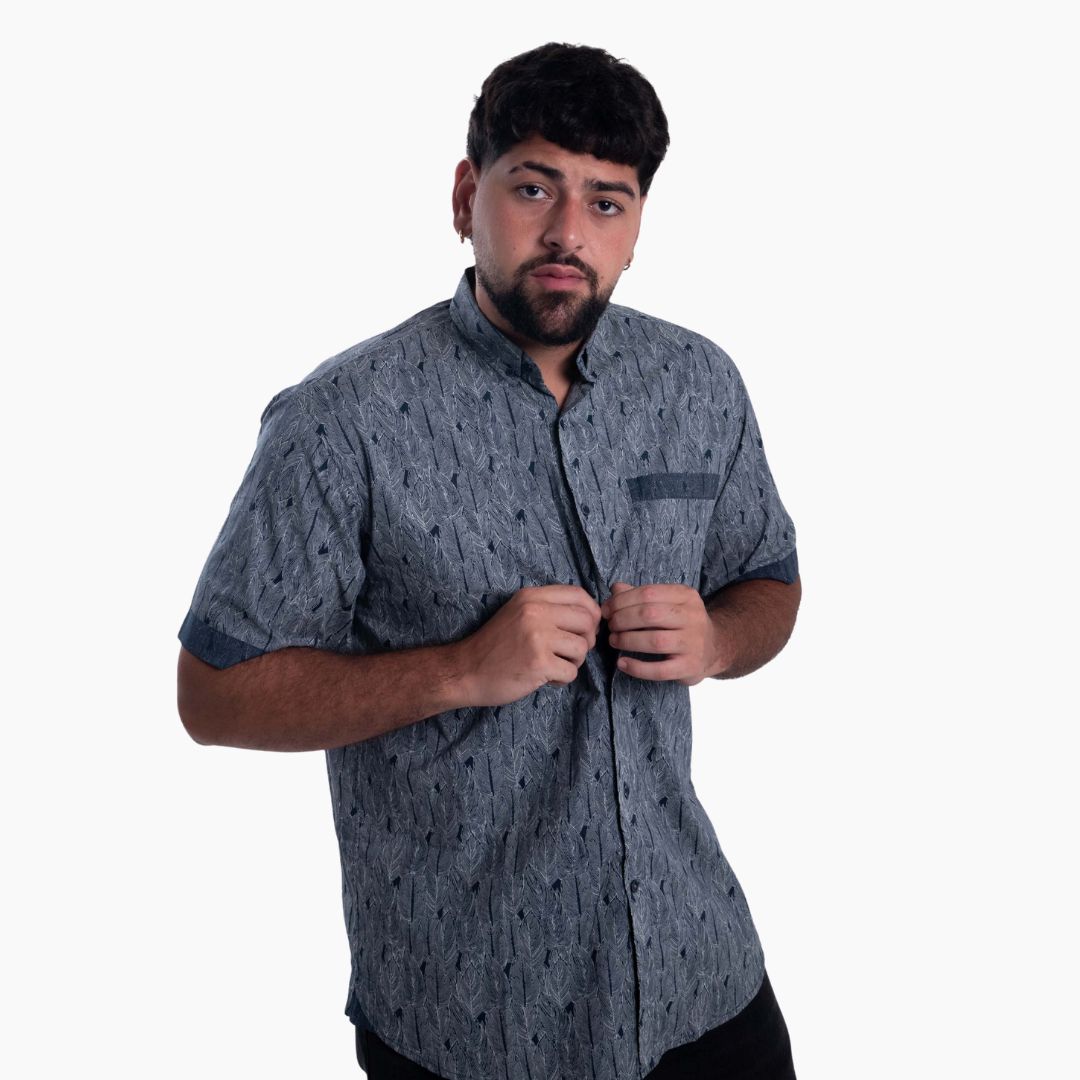Hombre posando con una camisa casual de manga corta en color gris con estampado geométrico de plumas y detalle de bolsillo.