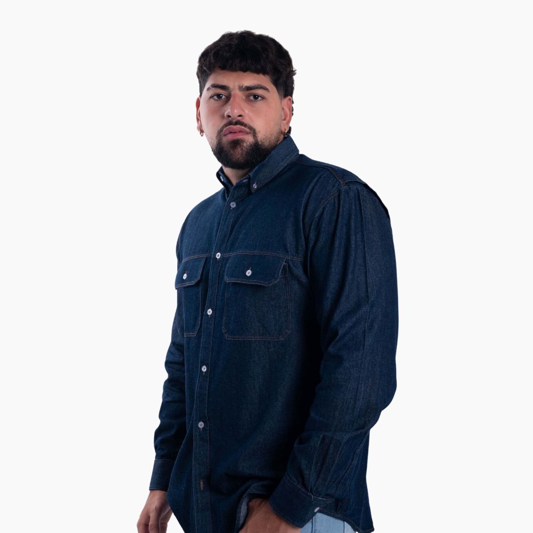 Un modelo posando con una camisa vaquera azul oscuro con dos bolsillos en el pecho.