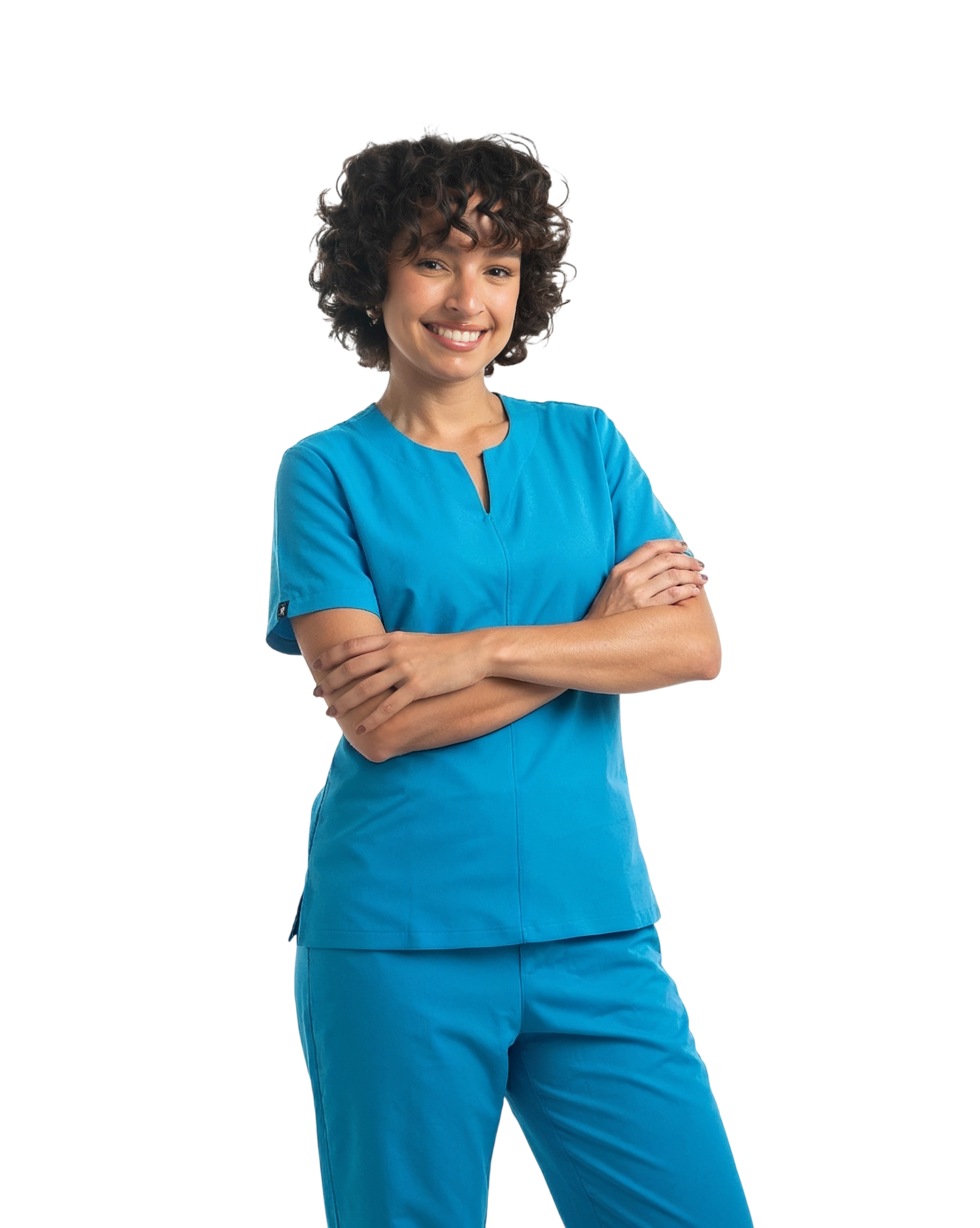 Mujer sonriente con cabello rizado posando con los brazos cruzados y vistiendo el uniforme médico Esmeralda en color azul celeste, compuesto por una filipina de manga corta con cuello estilizado y pantalón a juego sobre un fondo negro.